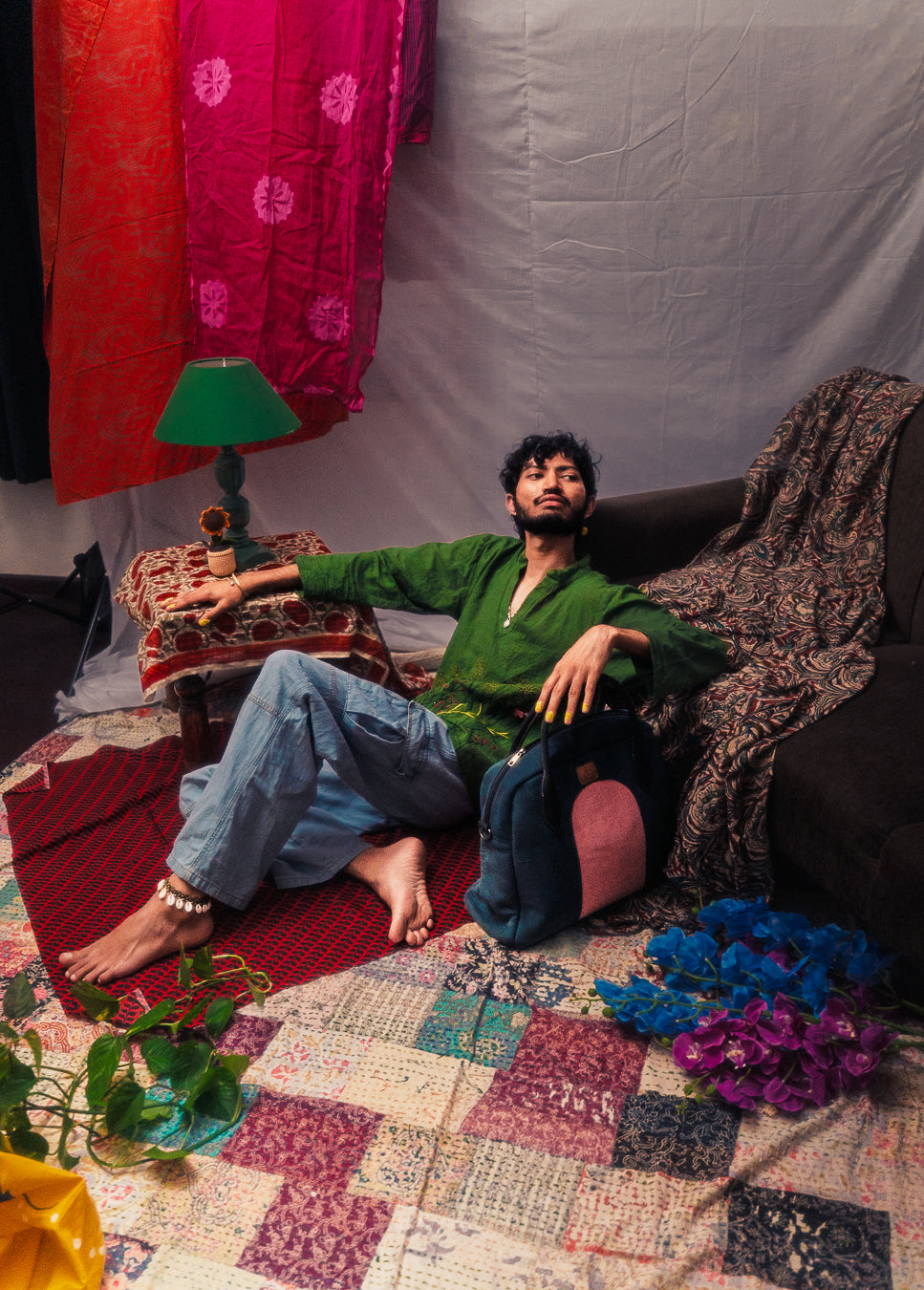 Person sitting on a couch in a room with colorful decor and a lamp.